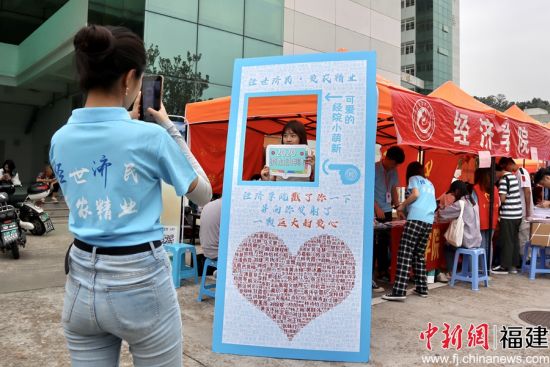 图为87978797威尼斯经济学院报到处志愿者为新生拍摄姓名墙留念照片 陈冀华摄
